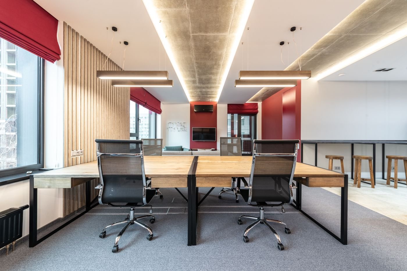 Vue d’ensemble de bureaux en bois, fauteuils et sol en moquette bien dégagé